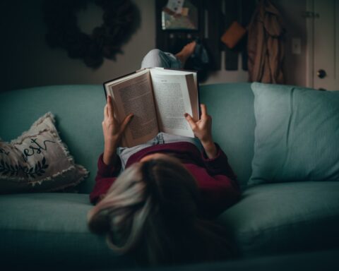 woman reading book on couch